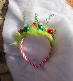 a green headband with red and green ornaments on it's side next to a brick wall