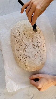 a person is carving a rock with a sharp knife on the white paper that they are holding