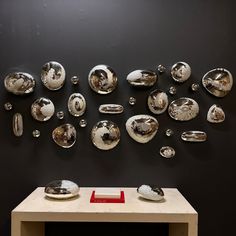 silver spoons are arranged on a black wall behind a table with a red plaque