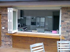 an open kitchen window with two chairs on the outside