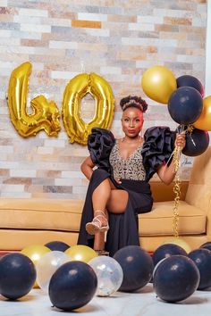 a woman sitting on a couch with balloons in front of her and the word love spelled out