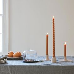 three candles are lit on a table with plates and bowls