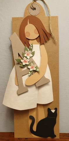 a paper bag with a girl holding a flower and a cat on the front, hanging from a string