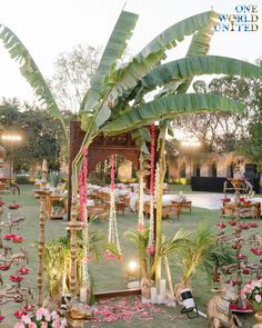 an outdoor wedding setup with flowers and greenery on the grass, surrounded by palm trees