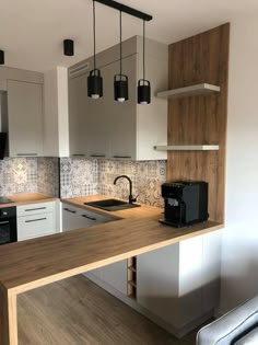 a kitchen with white cabinets and wooden counter tops, black appliances and hanging lights over the sink