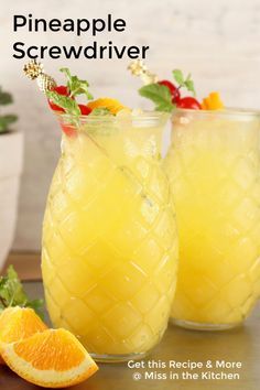 two glasses filled with orange juice and garnished with pineapple on the side