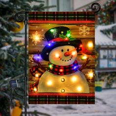 a lighted snowman is in front of a christmas tree