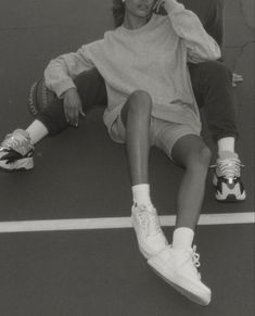 a man sitting on top of a tennis court holding a racquet to his ear