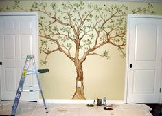 a tree painted on the wall in a room with two doors and a ladder next to it