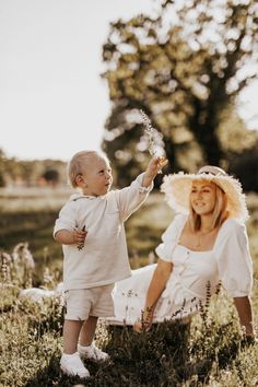 a woman holding a baby while sitting on the ground with a flower in her hand