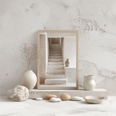 a white room with some vases and rocks on the table next to it,