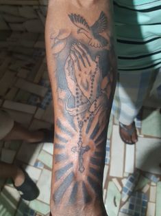 a man with a tattoo on his arm holding a rosary and dove in the center