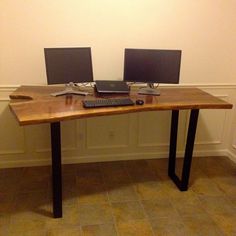 two computer monitors sitting on top of a wooden desk