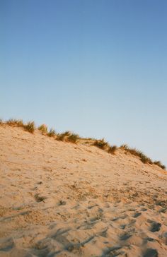 a person standing on top of a sandy beach next to a kite flying in the sky