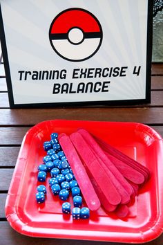 a red tray with blue balls in it next to a sign that says training exercise 4 balance