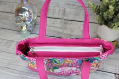 a pink handbag sitting on top of a wooden table next to a potted plant