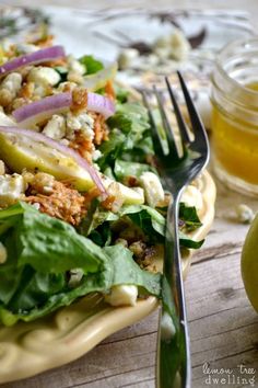 a close up of a salad on a plate with a fork and an apple in the background