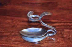 a silver spoon sitting on top of a wooden table next to a glass container with an object in it