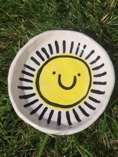 a white and black plate with a smiley face painted on it in the green grass