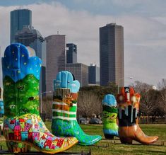 some very colorful boots sitting in the grass with tall buildings in the backgroud