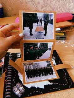 a person holding up two photos in front of a table