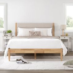 a bed with white sheets and pillows in a bedroom next to two nightstands on either side of the bed