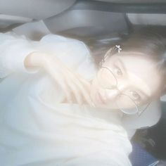 a woman wearing glasses and a white dress in the back seat of a car,