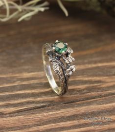 a close up of a ring on a wooden surface with flowers and leaves in the background