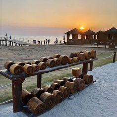 a bench made out of logs sitting on top of snow covered ground next to the ocean