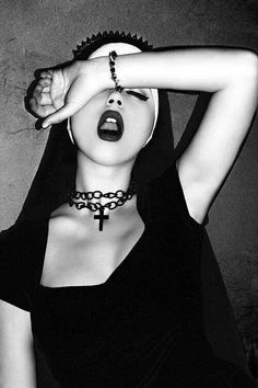 a woman with her hands on her head, wearing a choker and black dress