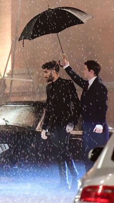 two men walking under an umbrella in the rain