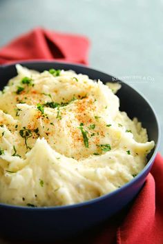 mashed potatoes with parsley in a blue bowl on a red cloth, ready to be eaten