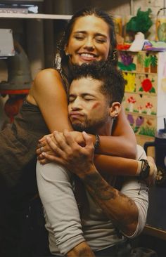 a man holding a woman in his arms while she smiles at the camera with her eyes closed