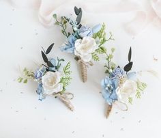 three boutonnieres with blue and white flowers on them