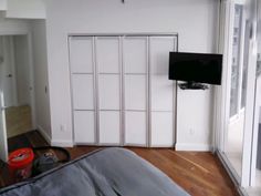 an empty bedroom with sliding doors and a flat screen tv mounted on the wall in front of it