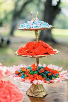 three tiered trays filled with colorful candies on top of a wooden table