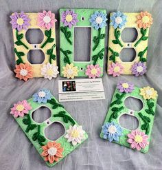 four flowered light switch covers are on display