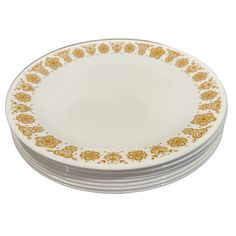 four white and gold plates stacked on top of each other