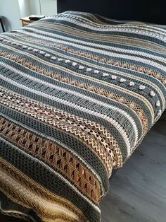 a bed covered in a multicolored blanket on top of a wooden floor