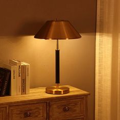 a lamp on top of a dresser next to a book