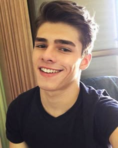 a young man is smiling for the camera while holding a donut in his hand