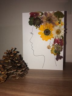 there is a card with flowers in the shape of a woman's head and pine cones