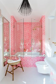 a bathroom with pink and white wallpaper, gold accents and a chandelier hanging from the ceiling