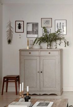 a living room with white walls and pictures on the wall above it's dresser