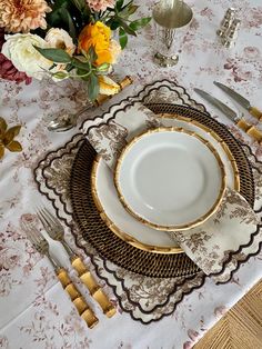 the table is set with gold and white dishes, silverware, and floral centerpieces