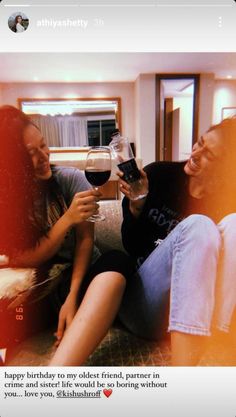 two people sitting on a couch holding wine glasses