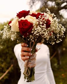 a woman holding a bouquet of red and white roses