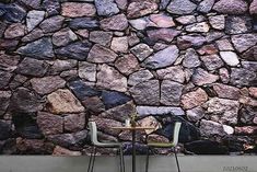 a stone wall with two chairs next to it