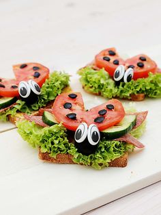 four sandwiches with tomatoes, lettuce and ladybugs on them