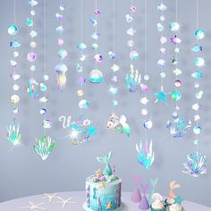 a cake and decorations on a table with a wall hanging in the background that says under the sea